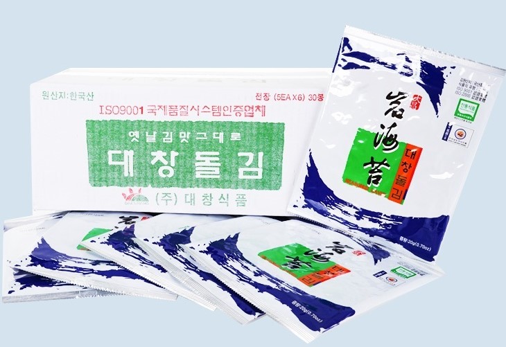 ISO9001 국제품질시스템인증업체, 옛날 김맛그대로 대창돌김 (주) 대창식품 이라 적힌 박스와 흰 배경에 짙은 파란색이 있고 대창 돌김이라고 쓰인 개별 포장된 김이 있는 사진