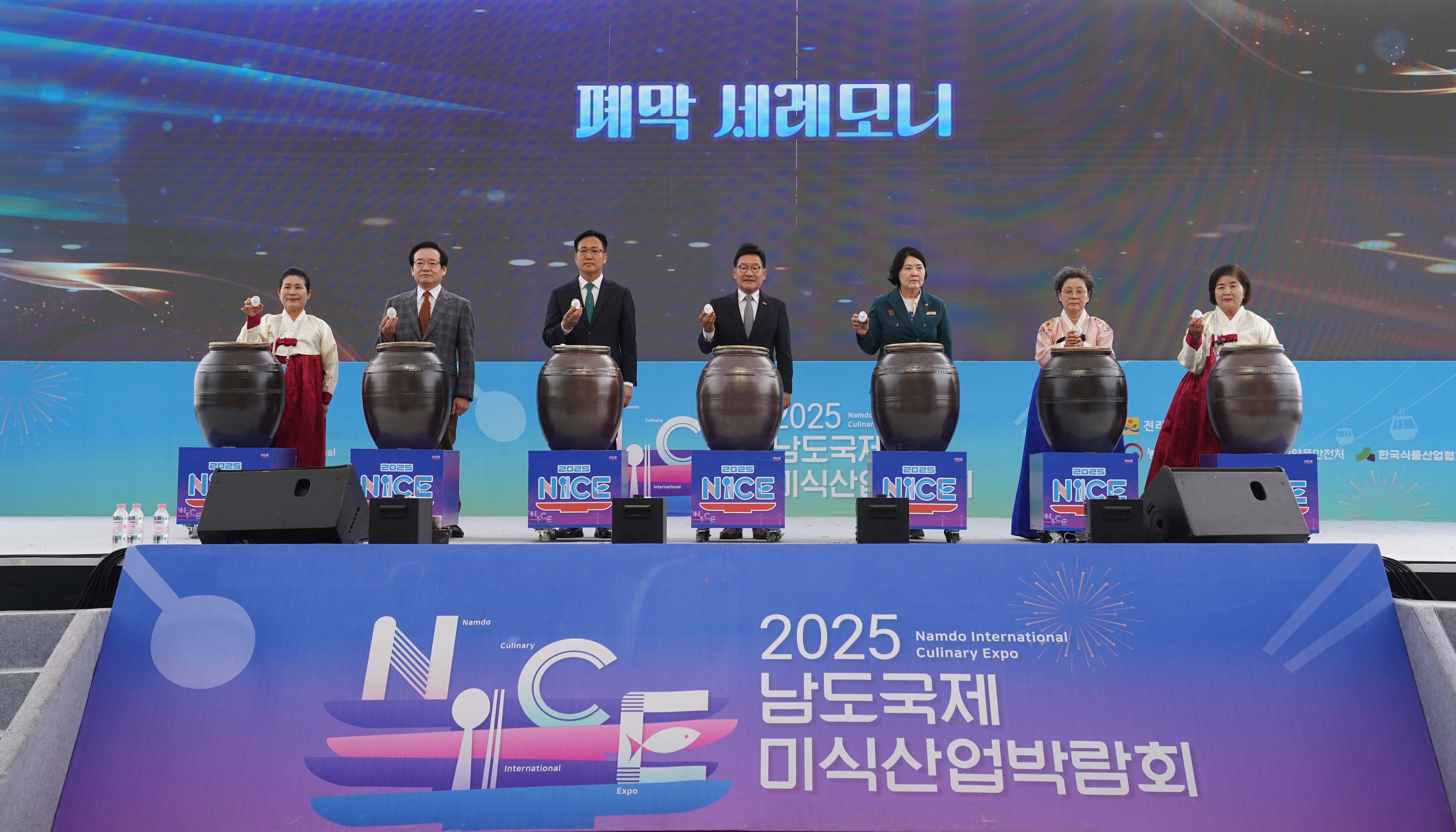 '폐막 세레모니'를 위해 내빈들이 무대 위 장독대 앞에 서서 소금 혹은 상징물을 들고 포즈를 취하는 모습. 하단에 '2025 남도국제미식산업박람회' 대형 로고가 보임.