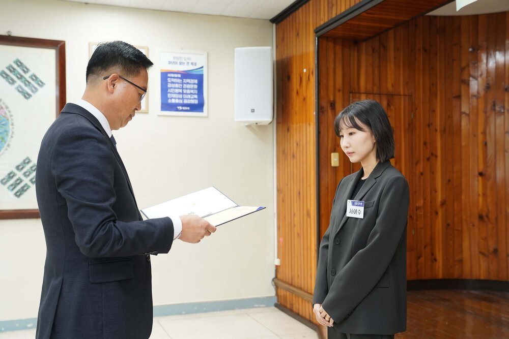 11월 정례조회로 정장을 입고 안경을 쓴 남성이 단발머리에 검은색 정장을 입은 서이수 수상자에게 상장을 수여 하고 있다.