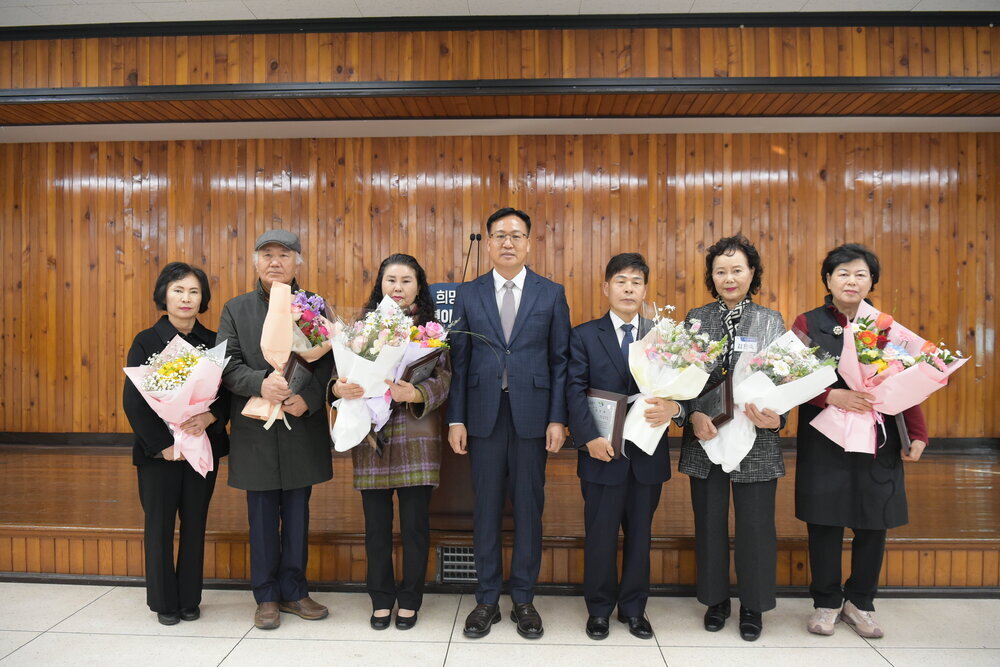 3월 정례조회 행사에서 정장을 입고 안경을 쓴 남성이 수상자들과 함께 기념촬영을 하고 있으며, 왼쪽부터 임화성, 강태진, 이경숙, 윤미현, 김은숙, 송희자가 꽃다발과 상패를 들고 일렬로 서 있다.