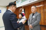 11월 정례조회로 정장을 입고 안경을 쓴 남성이 체크 무의 자켓을 입고 두손을 가지런이 모은 안호선 수상자에게 상패를 수여 하고 있다.