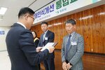 11월 정례조회로 정장을 입고 안경을 쓴 남성이 회색 정장을 입고 두속을 가지런히 모은 이노적 수상자에게 상패를 수여 하고 있다.