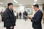 2026년 상반기 4급이하 정기인사로 정장을 입고 안경을 쓴 남성이 실내 행사장에서 한 남성에게 상장을 전달하며 내용을 읽고 있고, 남성은 검은 패딩을 입고 서 있으며 뒤쪽에는 참석자들이 줄지어 서서 행사를 지켜보고 있다.